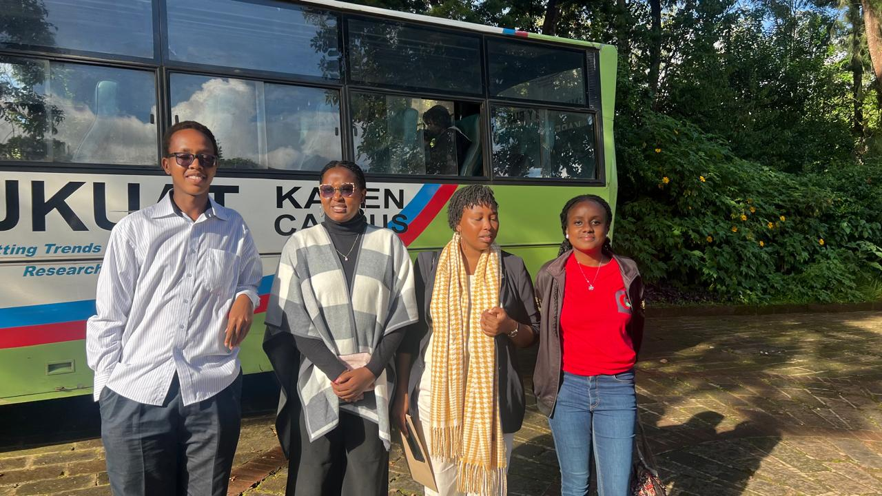 JKUSA team members standing beside the campus bus